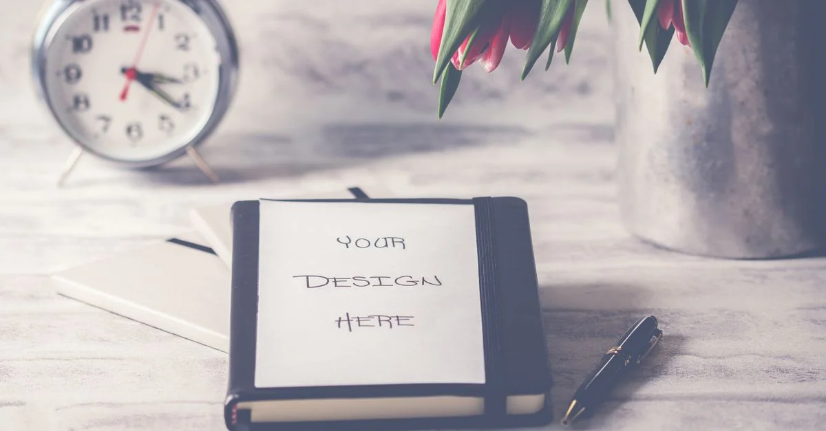 Scène de bureau élégante avec des tulipes, une horloge et un carnet avec une couverture personnalisable.